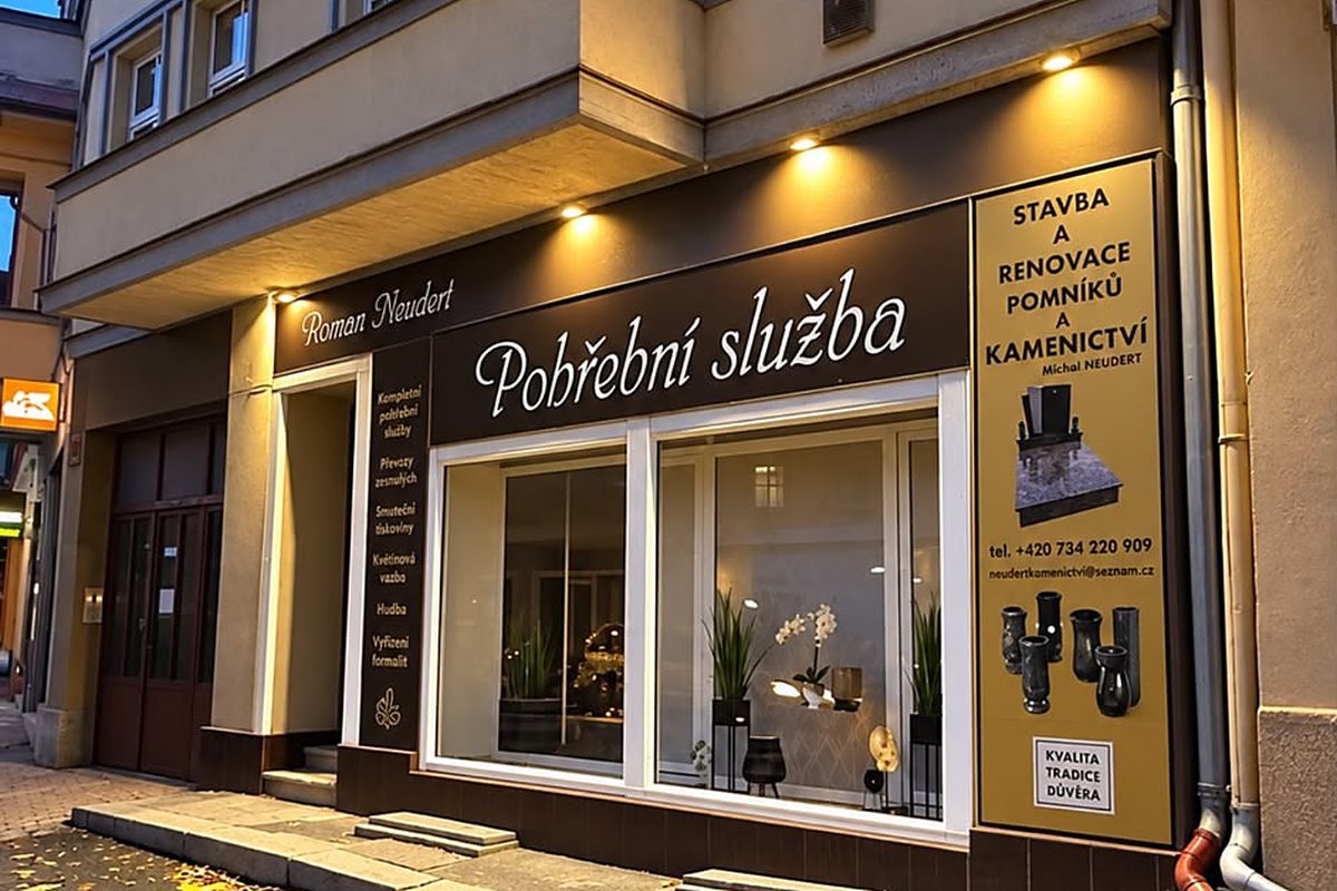 Výloha pohřební služby Roman Neudert s osvětleným nápisem za soumraku